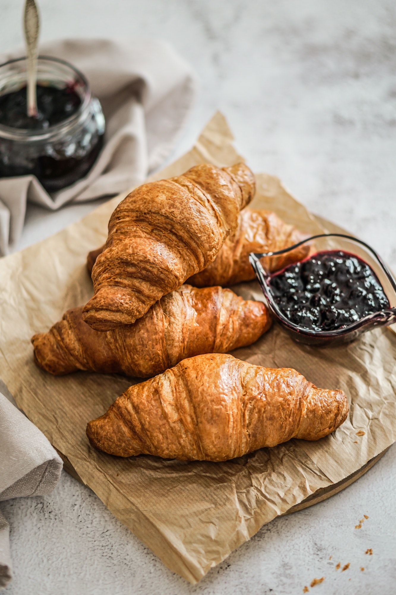 french fresh croissant with blackberry jam on a bakery paper and grey background.jpg